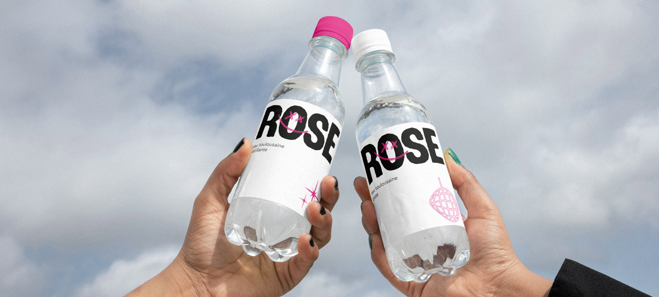 Projet Rose festival : 2 mains qui tchinent avec une bouteille chacune floquées aux couleurs du festival (une bouteille d'eau plate et une bouteille d'eau gazeuse)